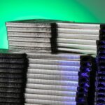 Close-up of stacked metallic discs reflecting green and blue light.