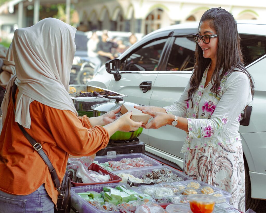 Two women exchanging food at a street market in West Java, Indonesia.