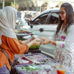 Two women exchanging food at a street market in West Java, Indonesia.
