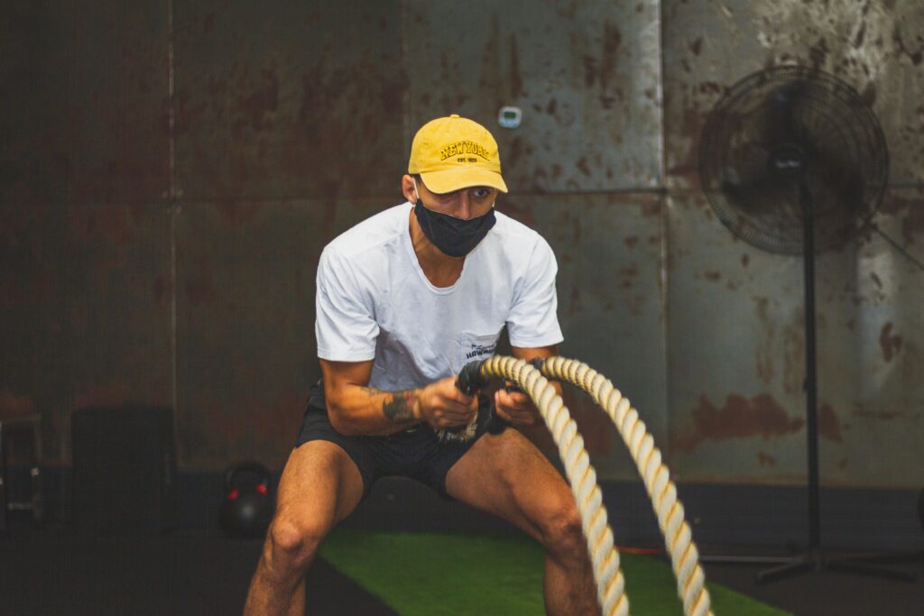 Focused man exercising with battle ropes indoors, showcasing strength and fitness.