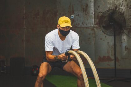 Focused man exercising with battle ropes indoors, showcasing strength and fitness.