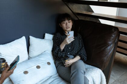 Woman sitting on couch with coffee and smartphone, enjoying a relaxing break indoors.