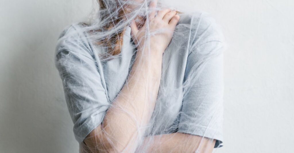 A woman metaphorically trapped in a spider web depicting anxiety and entrapment.